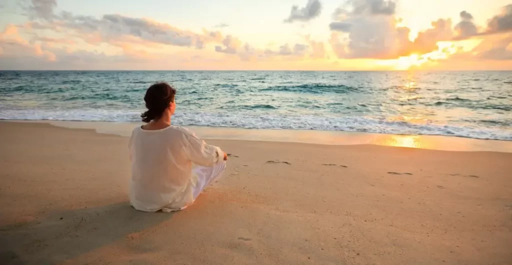 woman pausing on beach to find stillness from overdoing noise
